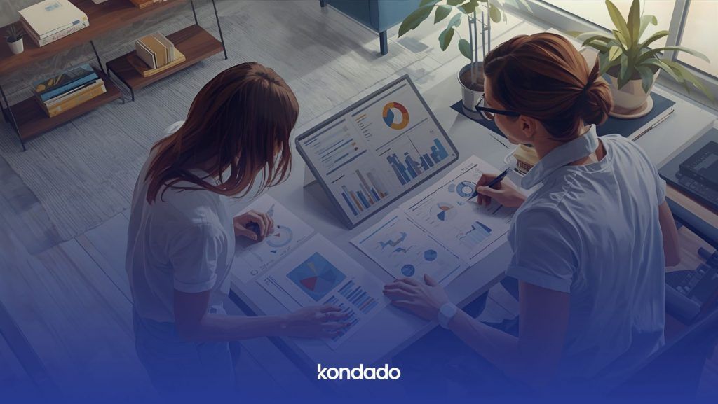 Duas mulheres analisam um dashboard de dados em tablet e relatórios impressos em um escritório. Imagem de IA.